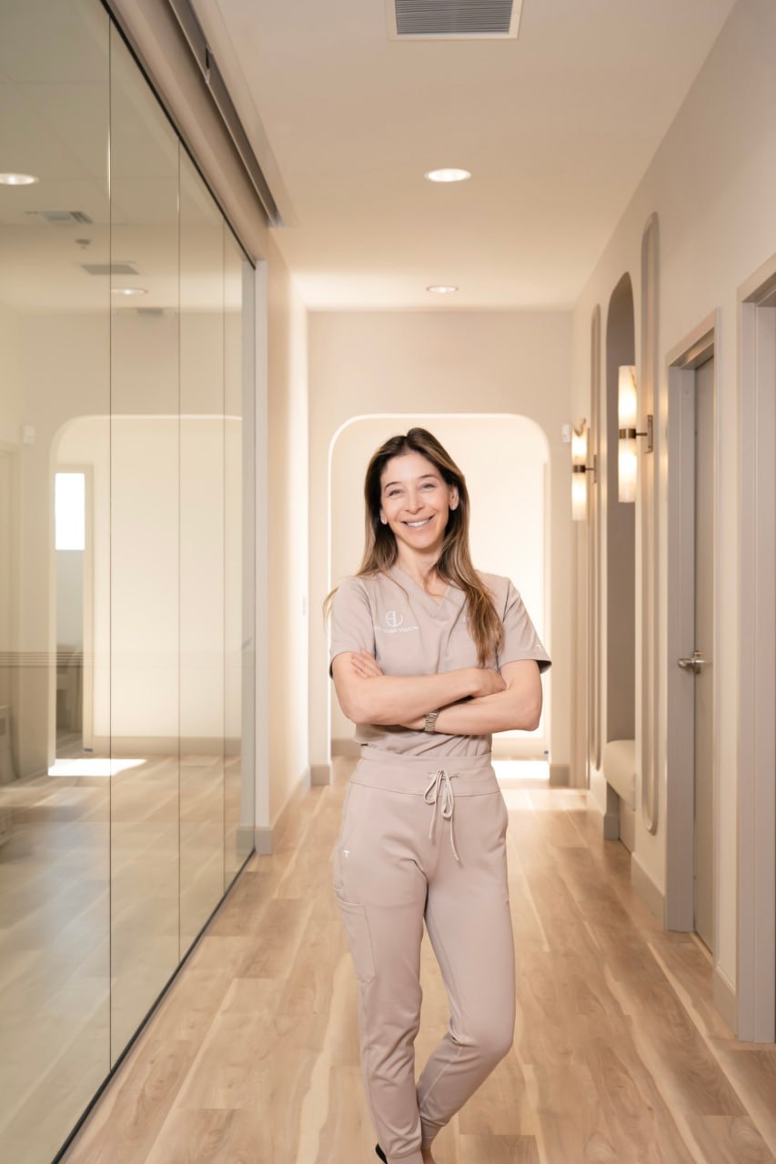 Dr. Emily Schorr smiling with arms crossed in the Schorr Vision hallway, Las Vegas custom lens replacement surgeon